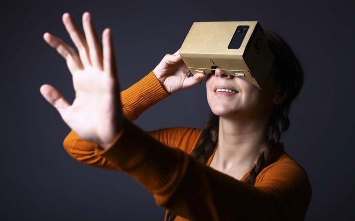 Color shot of a young woman looking through a cardboard, a device with which one can experience virtual reality on a mobile phone.; Shutterstock ID 258534815; user id: 13274325; user email: ken@ifanr.com; user_country: China; discount: 38%