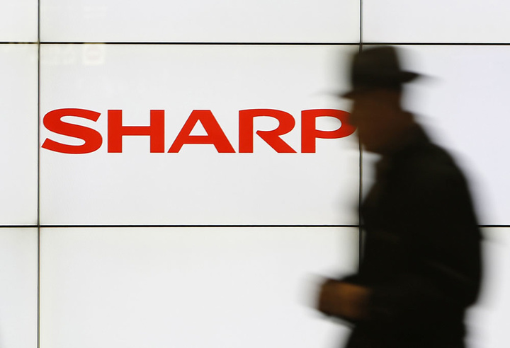 File photo of a pedestrian walking past a logo of Sharp Corp at a train station in Tokyo