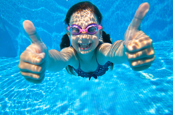 little girl dives into the water and shows the gesture OK