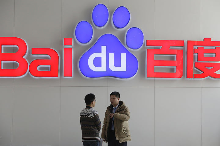 People talk in front of a Baidu's company logo at Baidu's headquarters in Beijing