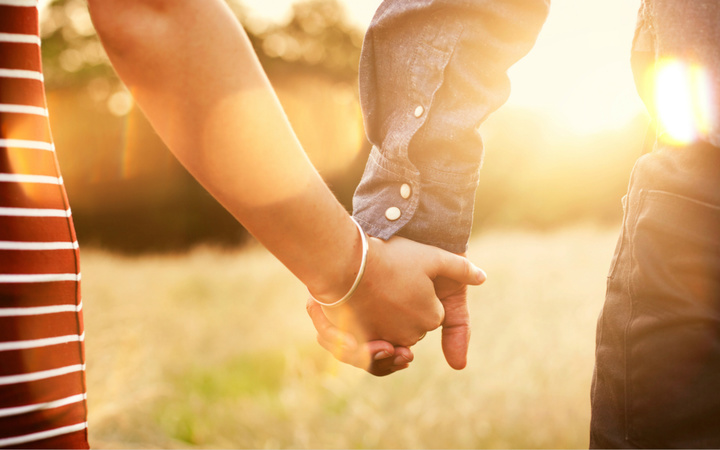 Young couple holding hands with sun-flare.