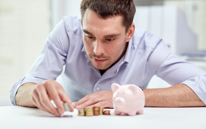 business, people, finances and money saving concept - businessman with piggy bank and coins at office