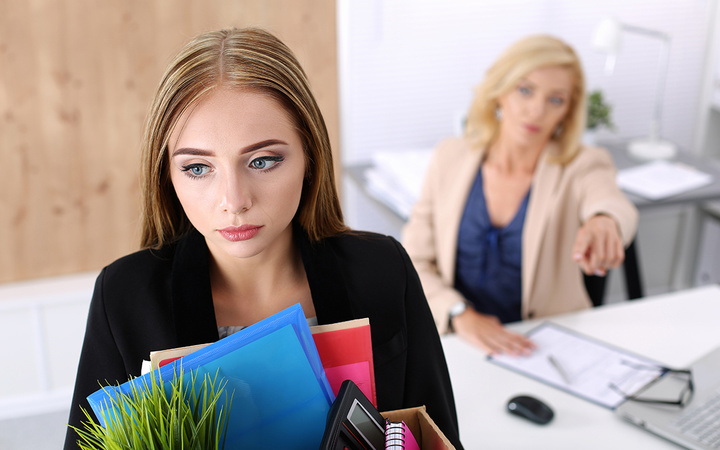 Boss dismissing an employee. Dejected fired office worker carrying a box full of belongings.