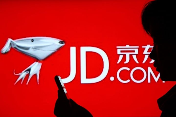 "A woman uses her mobile phone in front of an advertisement of JD.com (360Buy) in Jinan city, east Chinas Shandong province, 23 April 2013. "