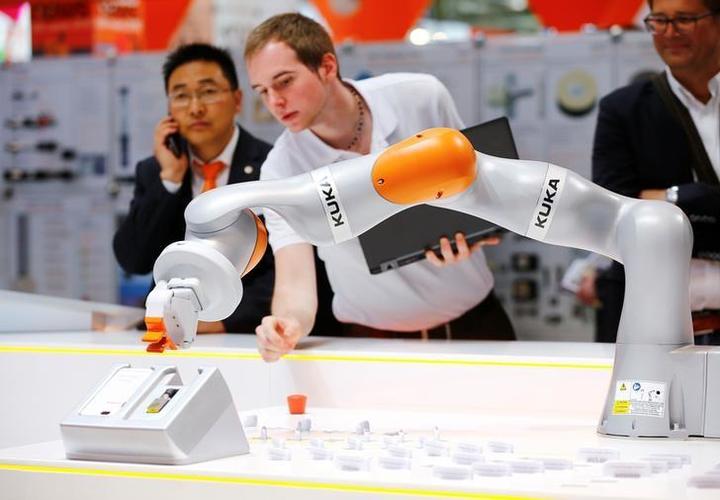 A Kuka technician programs a robot arm of German industrial robot maker Kuka at the company's stand during the Hannover Fair in Hanover, Germany, April 25, 2016. REUTERS/Wolfgang Rattay